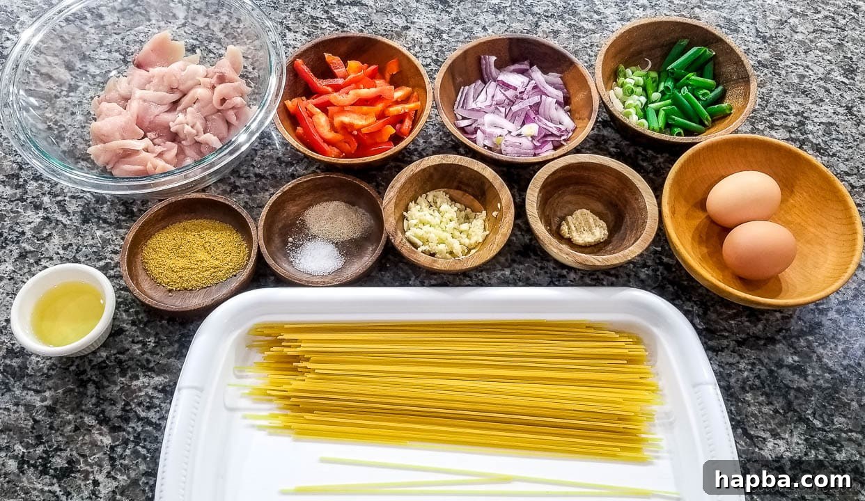 A collection of fresh ingredients laid out, including uncooked spaghetti, chicken breast, bell peppers, onions, garlic, ginger, and eggs, ready for the spaghetti stir fry.