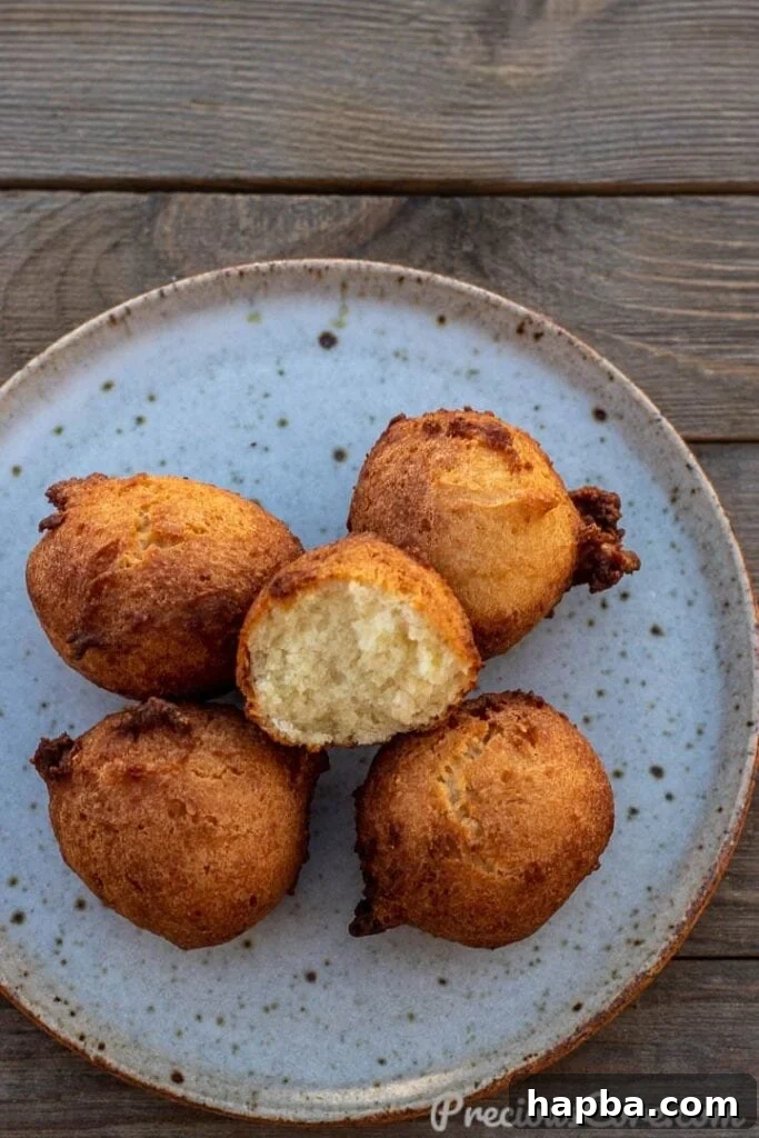 Irresistible Coconut Doughnuts 2 Coconut doughnuts on a plate with one opened up, showcasing the soft interior