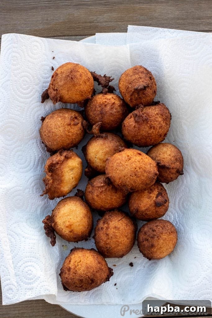 Irresistible Coconut Doughnuts 5 Pile of warm coconut doughnuts on paper towel to drain oil