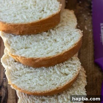 Slices of incredibly soft and fluffy homemade sandwich white bread on a rustic chopping board, ready to be enjoyed.