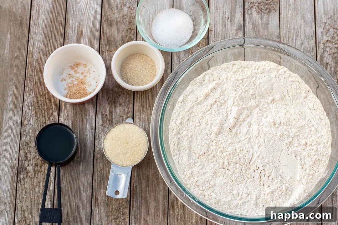 Effortless Homemade Sandwich Bread 4 Bowls and measuring cups filled with the simple ingredients required for the Easy Sandwich Bread Recipe, including flour, yeast, sugar, oil, water, salt, and nutmeg.