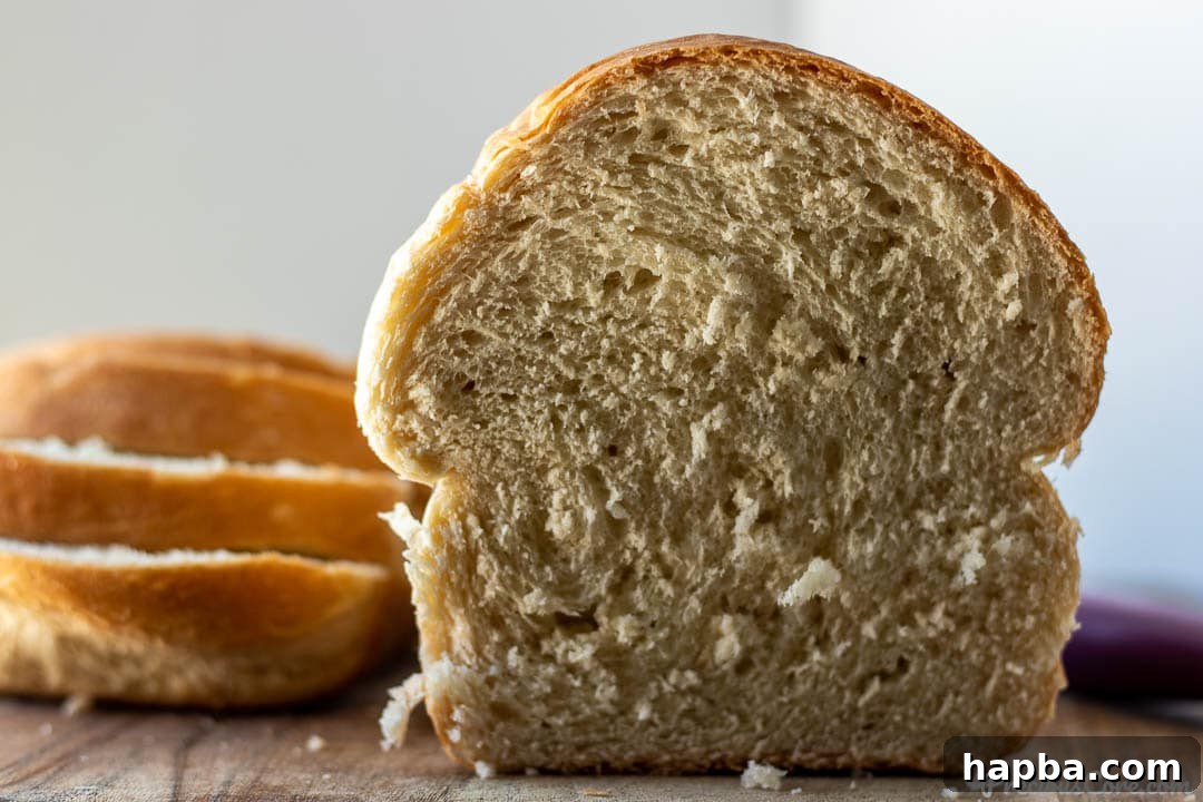 Effortless Homemade Sandwich Bread 9 A half loaf of freshly baked homemade bread positioned next to several perfectly cut slices, showcasing its soft interior and golden crust.