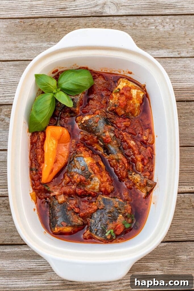 A bowl of rich, red Tomato Fish Stew, garnished with fresh herbs, ready to be enjoyed.