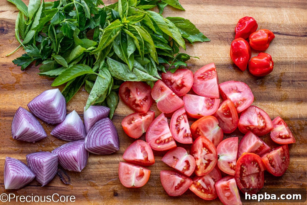 African Fire Sauce 3 Tomatoes, habanero peppers, onions, and herbs on a cutting board.