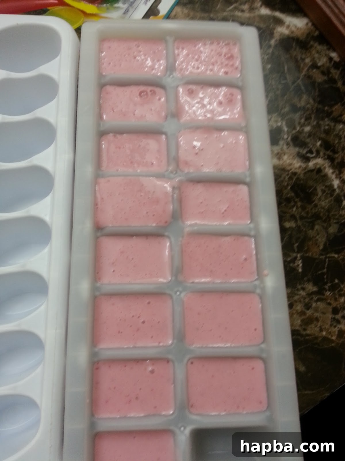 Filling Ice Cube Trays with Popsicle Mixture Yogurt mixture poured into ice cube trays