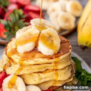 Stack of banana slices on a plate, banan slices on the stack and maple syrup pouring on top