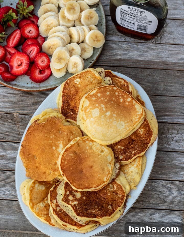A beautiful platter featuring a generous stack of banana pancakes, artfully arranged with fresh banana slices and bright red strawberries on the side.