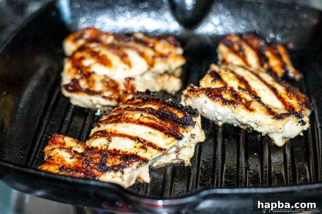 Chicken thighs sizzling on a grill pan