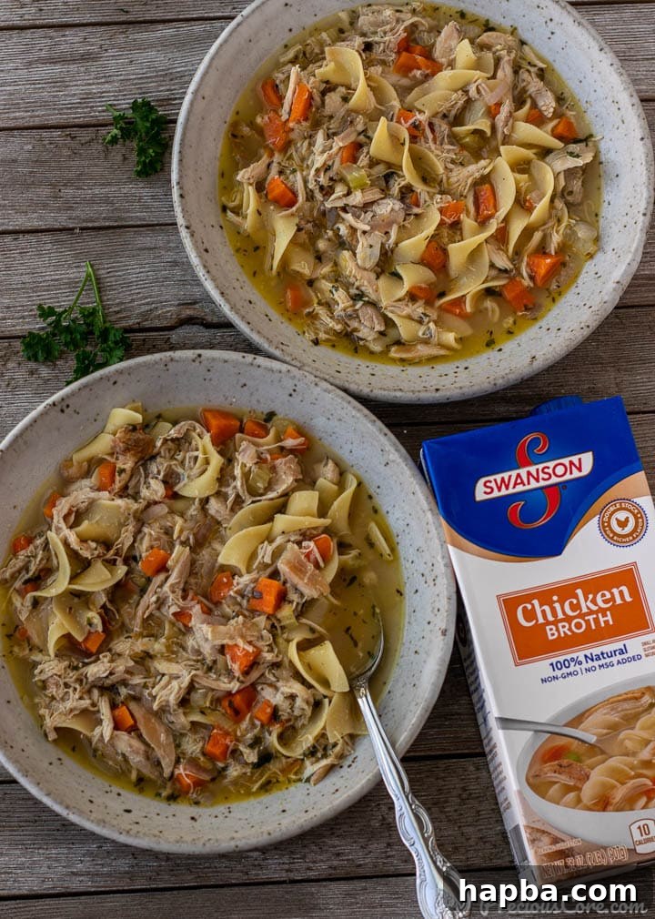 Two bowls of chicken noodle soup with a carton of Swanson Chicken Broth on the side, highlighting the key ingredient.