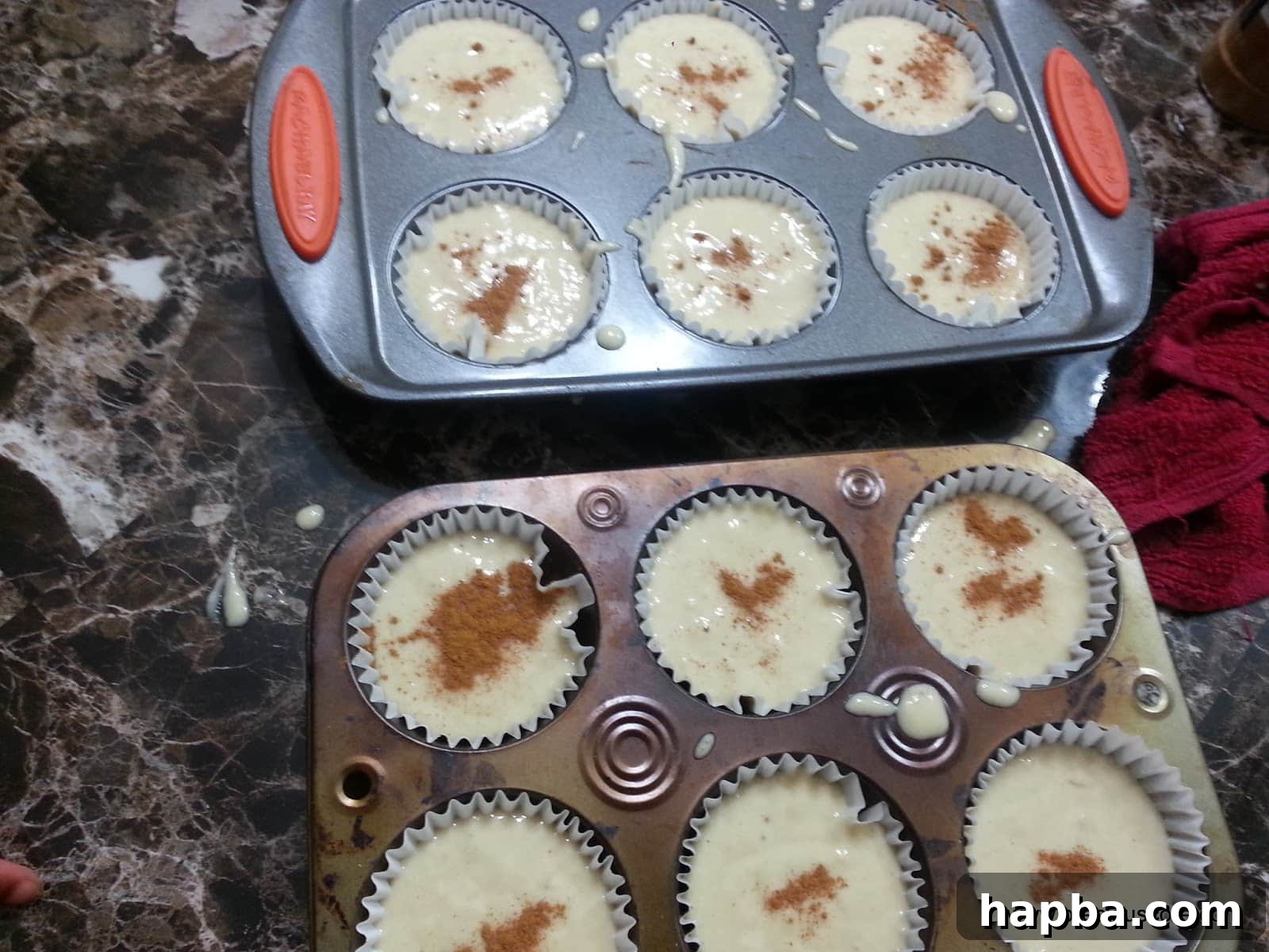 Banana cake batter in a muffin pan topped with a generous sprinkle of cinnamon powder.