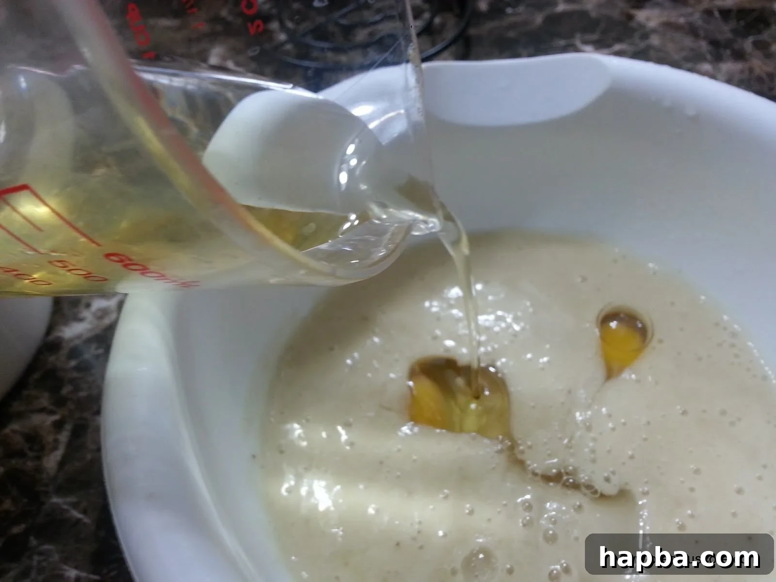 Vegetable oil being poured into the banana and egg mixture.