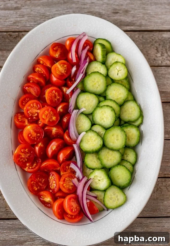 Vibrant Cucumber, Tomato, and Onion Medley 4 A vibrant mix of chopped cucumbers, tomatoes, and thinly sliced red onions on a platter, ready for dressing.