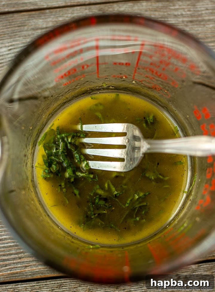 Vibrant Cucumber, Tomato, and Onion Medley 5 A measuring cup filled with vibrant green basil lemon salad dressing.