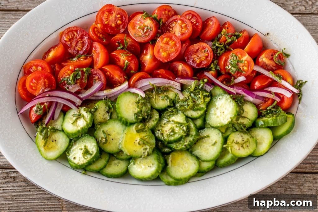 Vibrant Cucumber, Tomato, and Onion Medley 6 Cucumber tomato onion salad on a platter with basil lemon dressing drizzled generously over the top.