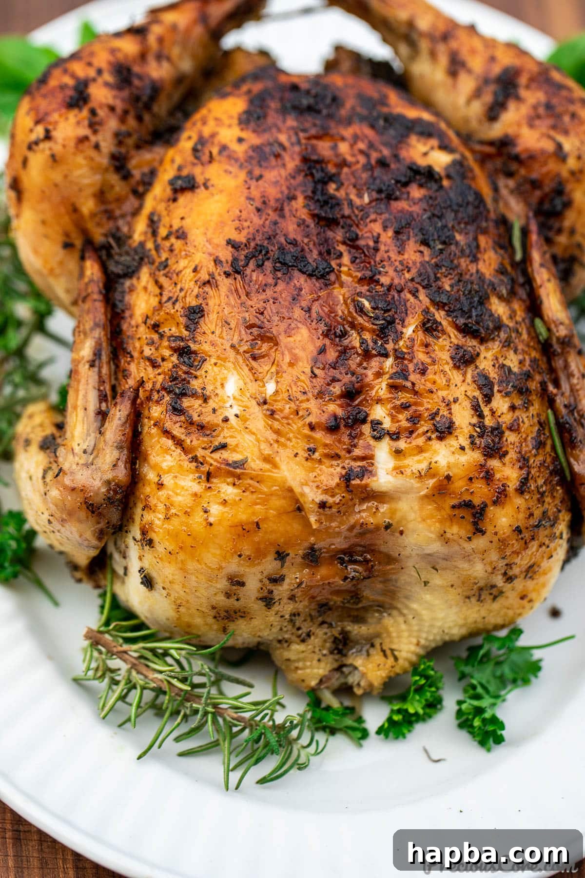 Succulent Herb Roasted Chicken 5 Whole herb roasted chicken on a platter, beautifully garnished with fresh herbs and bright lemon wedges, ready to be served.