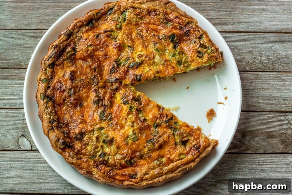 Effortless Quiche Delight 4 A whole quiche with a slice removed, showing the layers of crust and filling.
