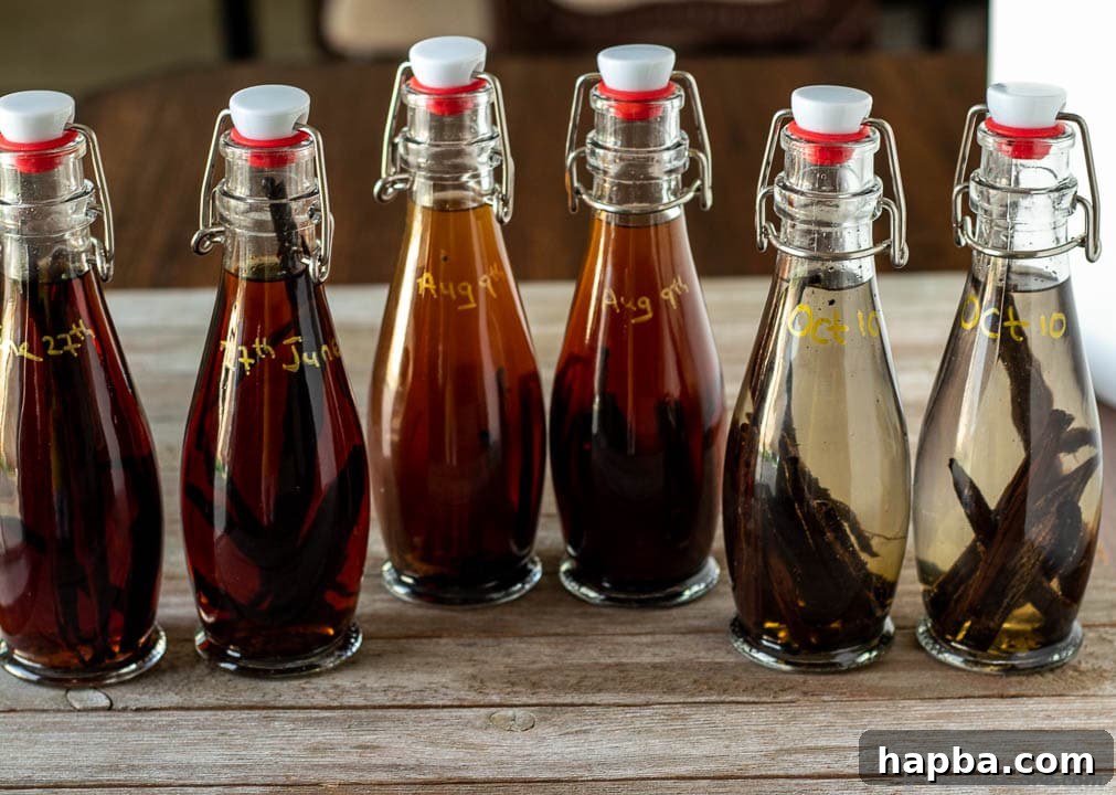 Pure Vanilla Perfection From Your Kitchen 4 Three glass bottles of varying sizes filled with homemade vanilla extract, displaying different shades of amber and containing vanilla bean pieces.
