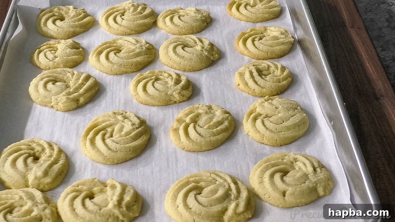 A baking sheet filled with freshly baked, golden-brown butter cookies, just out of the oven.