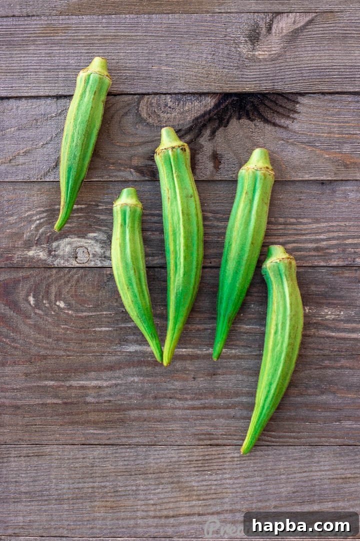 Vibrant African Okra Soup 5 Fresh green okra pods arranged neatly on a rustic wooden board, ready for preparation.