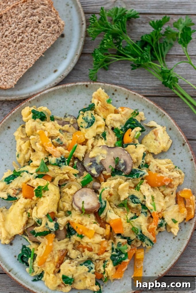 Colorful Morning Scramble 4 A generous serving of scrambled eggs with vegetables on a plate, accompanied by whole wheat toast.