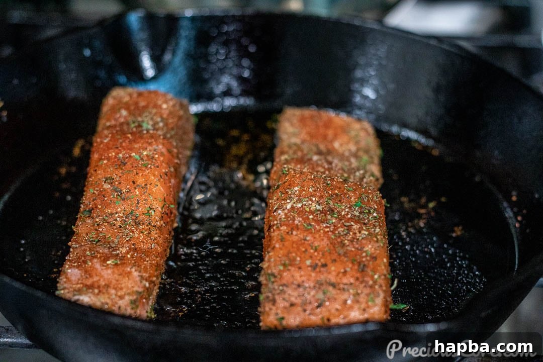 Golden Pan Seared Salmon 8 Salmon fillets sizzling in a hot cast iron skillet, showing the beginning of a perfect sear.