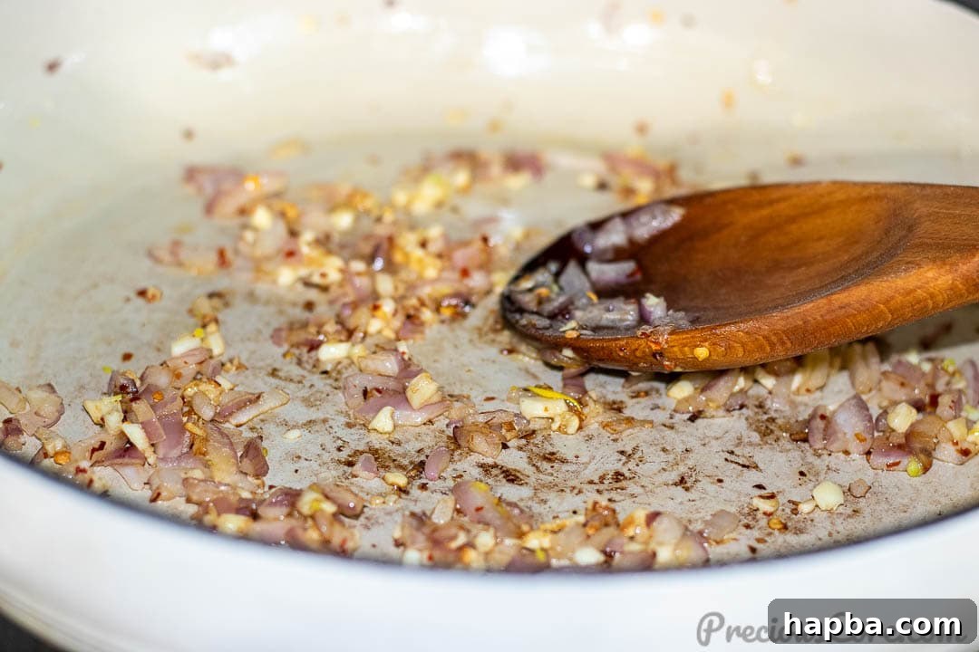Diced onions being sautéed in a pot, turning translucent.