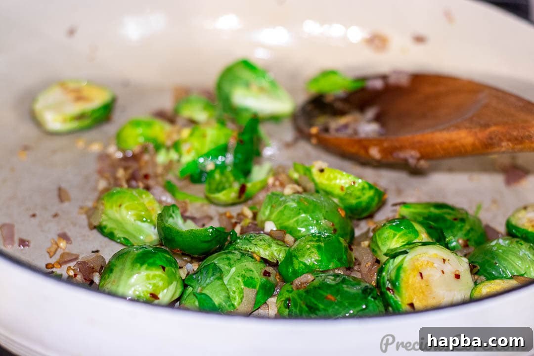 Brussels sprouts being added to a hot pot with sautéed onions and garlic.