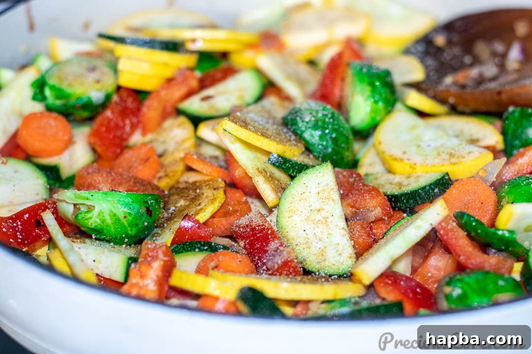 Sautéed vegetables in a pot with seasonings sprinkled on top, ready to be tossed.