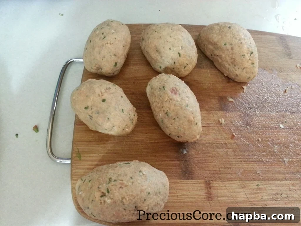Several fish-coated Scotch Eggs neatly arranged, ready for breadcrumbing