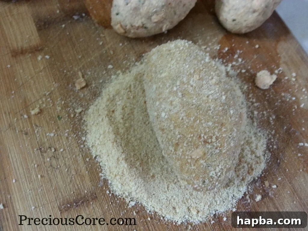A fish Scotch Egg being rolled in breadcrumbs