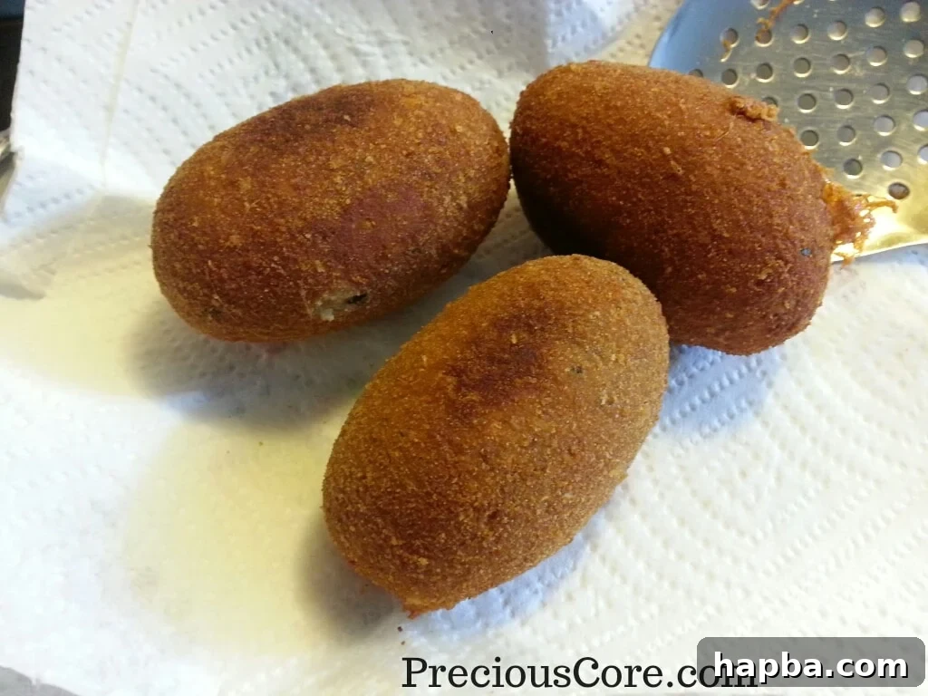 Fried fish Scotch Eggs resting on paper towels to drain excess oil