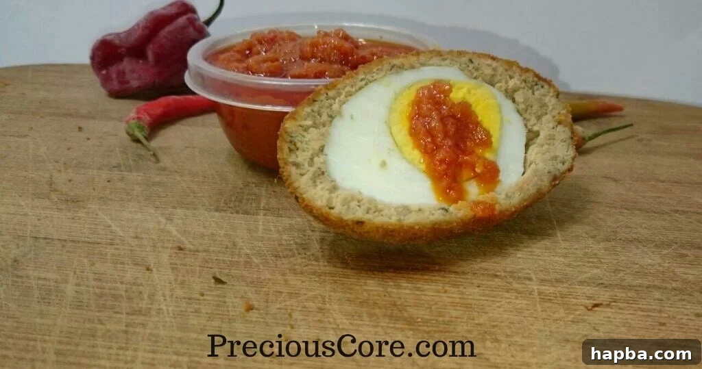 A plate of golden brown fish Scotch Eggs with a side of pepper sauce