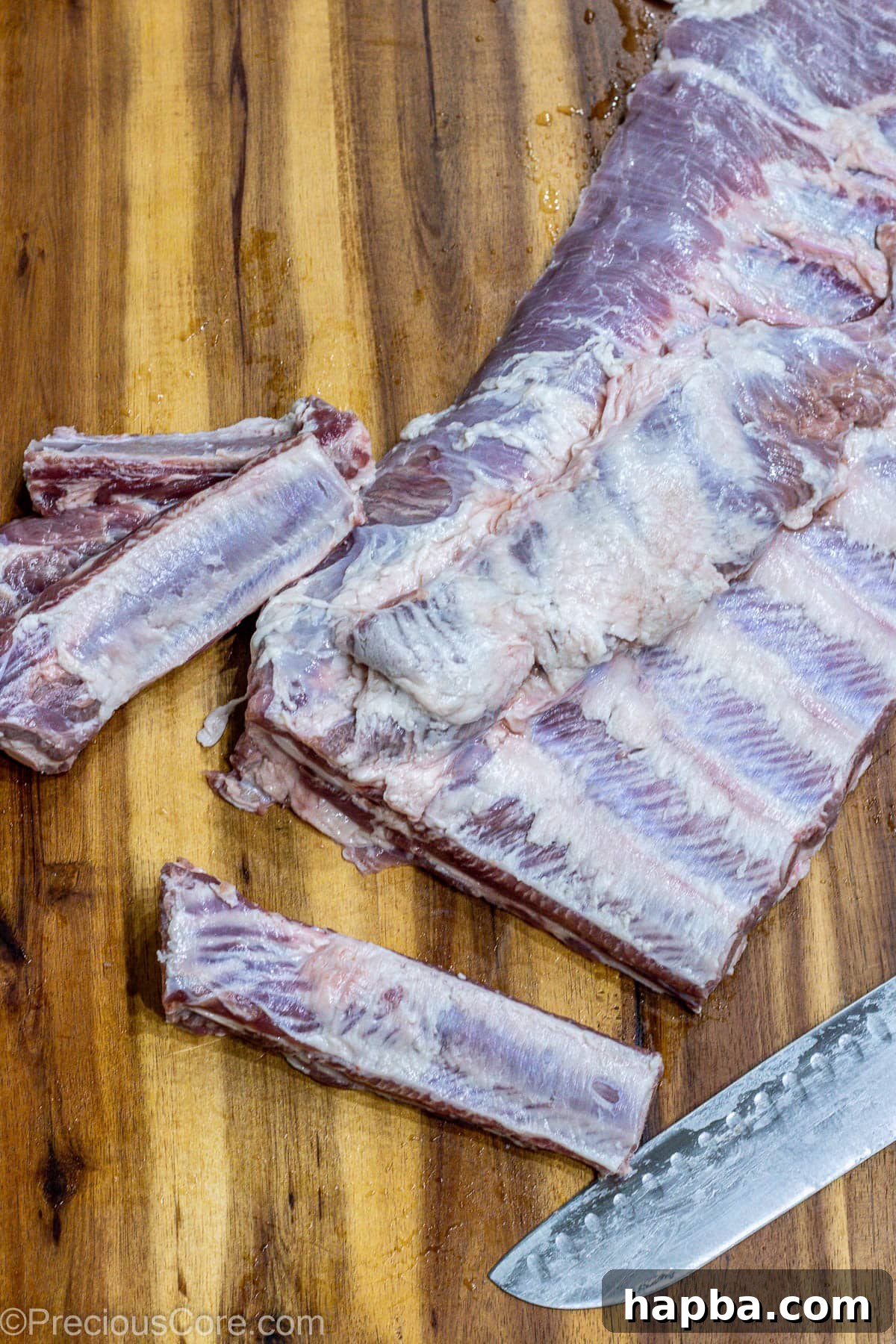 Tender Dry-Rubbed Ribs 5 A rack of ribs meticulously cut into individual portions on a wooden cutting board, ready for seasoning.