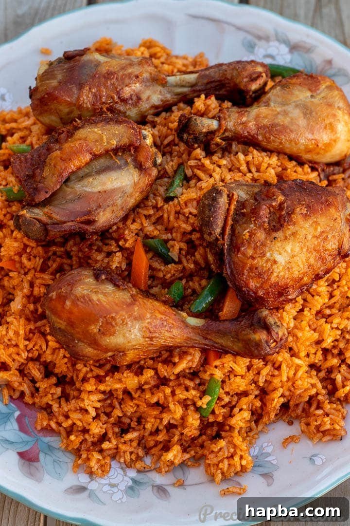 Jollof Rice on a serving platter with cooked chicken thighs and drumsticks on top