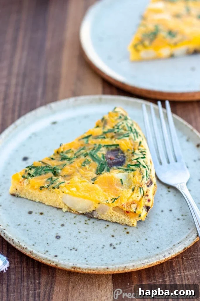 Hearty Potato Egg Bake 3 A perfectly portioned slice of Potato Frittata, showcasing its fluffy texture and golden crust, served on a white plate.