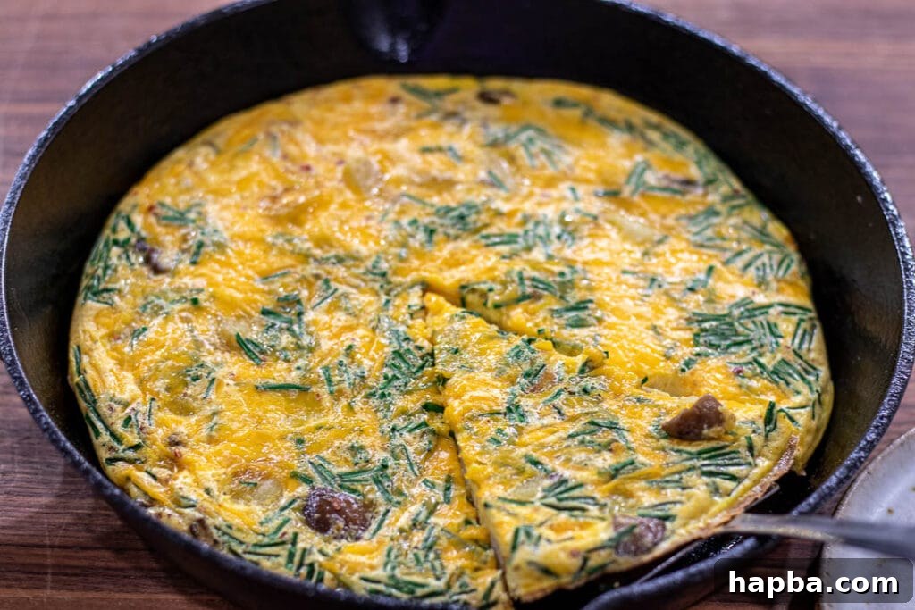 Hearty Potato Egg Bake 6 A fully baked Potato Frittata, golden brown and puffed, cooling in a cast iron skillet, ready to be sliced.