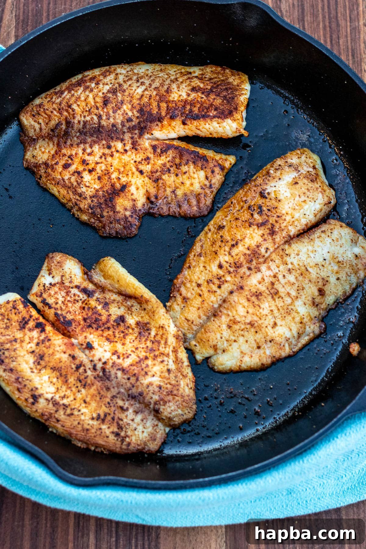 Zesty Lemon Butter Tilapia 5 Tilapia fillets cooking in a hot cast iron pan, achieving a golden crust.