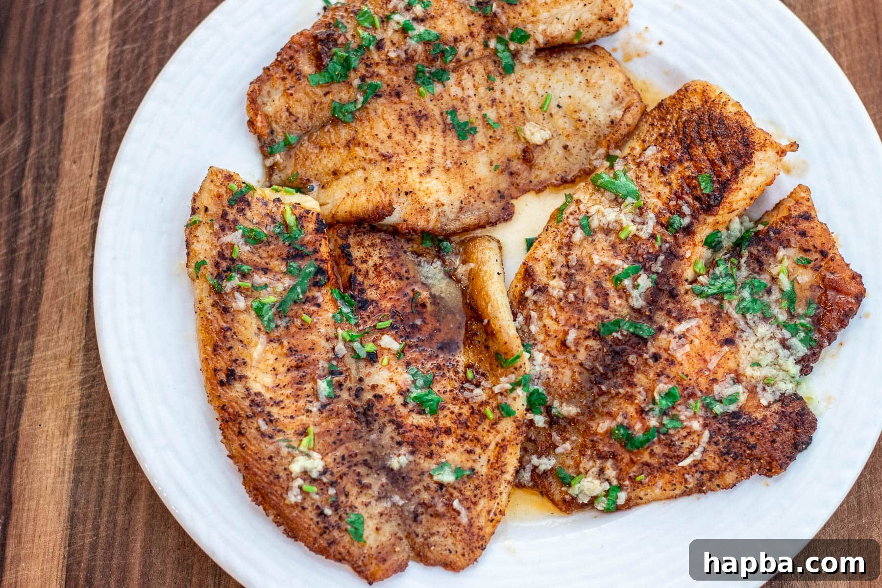 Zesty Lemon Butter Tilapia 6 Beautiful landscape shot of cooked lemon butter tilapia with fresh herbs.