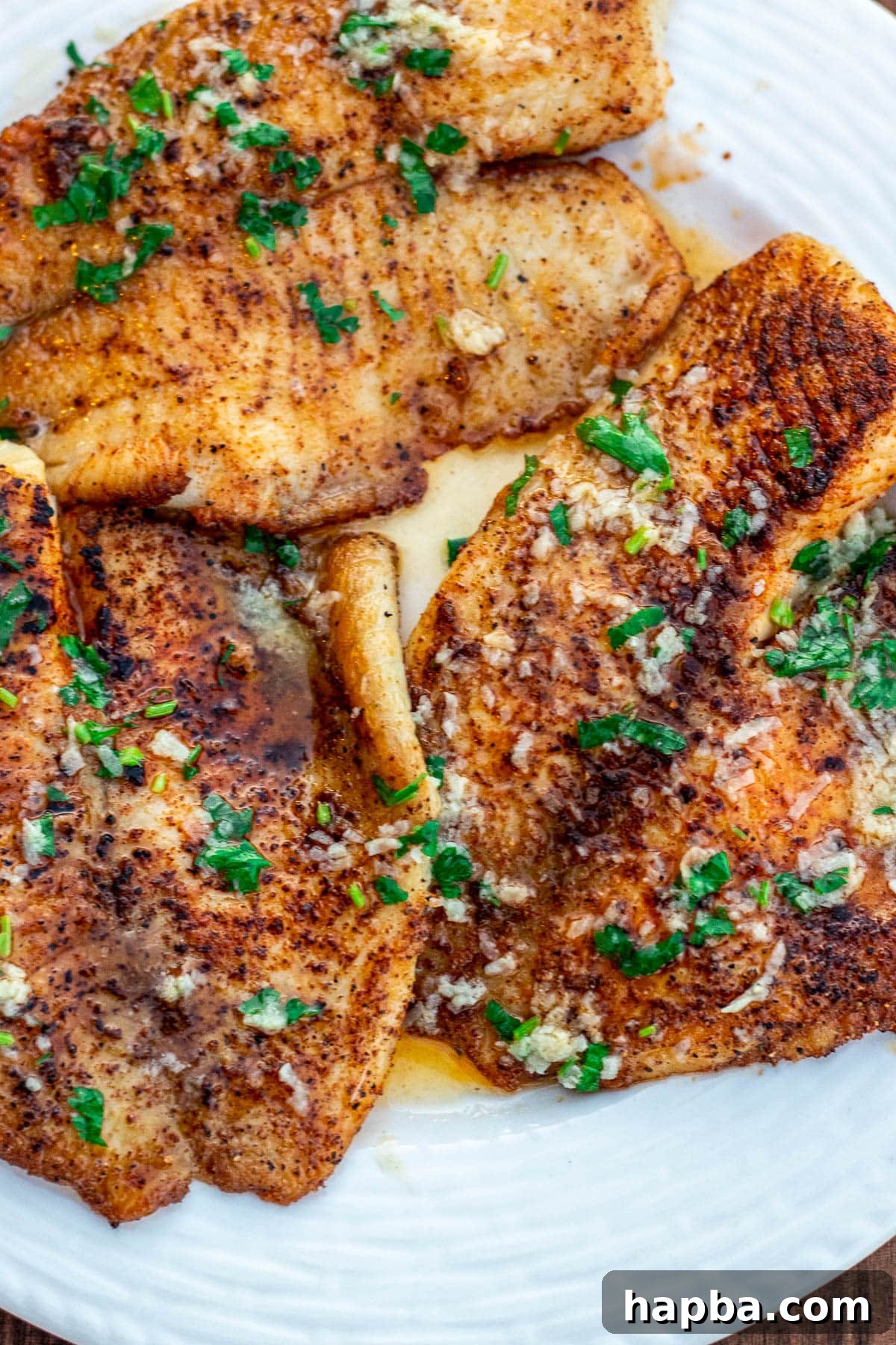 Zesty Lemon Butter Tilapia 7 Cooked tilapia fillets generously coated in lemon butter sauce, ready for serving.