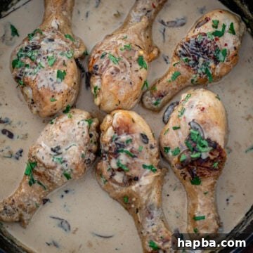 Chicken drumsticks in creamy sauce, beautifully presented in a cast iron skillet.