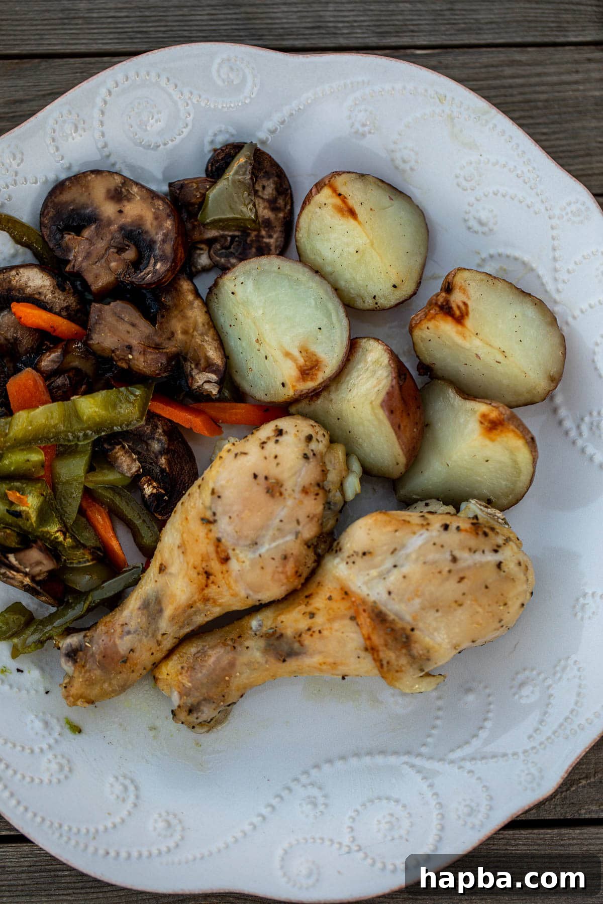 One Pan Golden Roasted Chicken and Vegetables 3 A perfectly portioned plate of golden roasted chicken drumsticks, fluffy potatoes, and colorful sautéed vegetables, showcasing a balanced and appealing meal.
