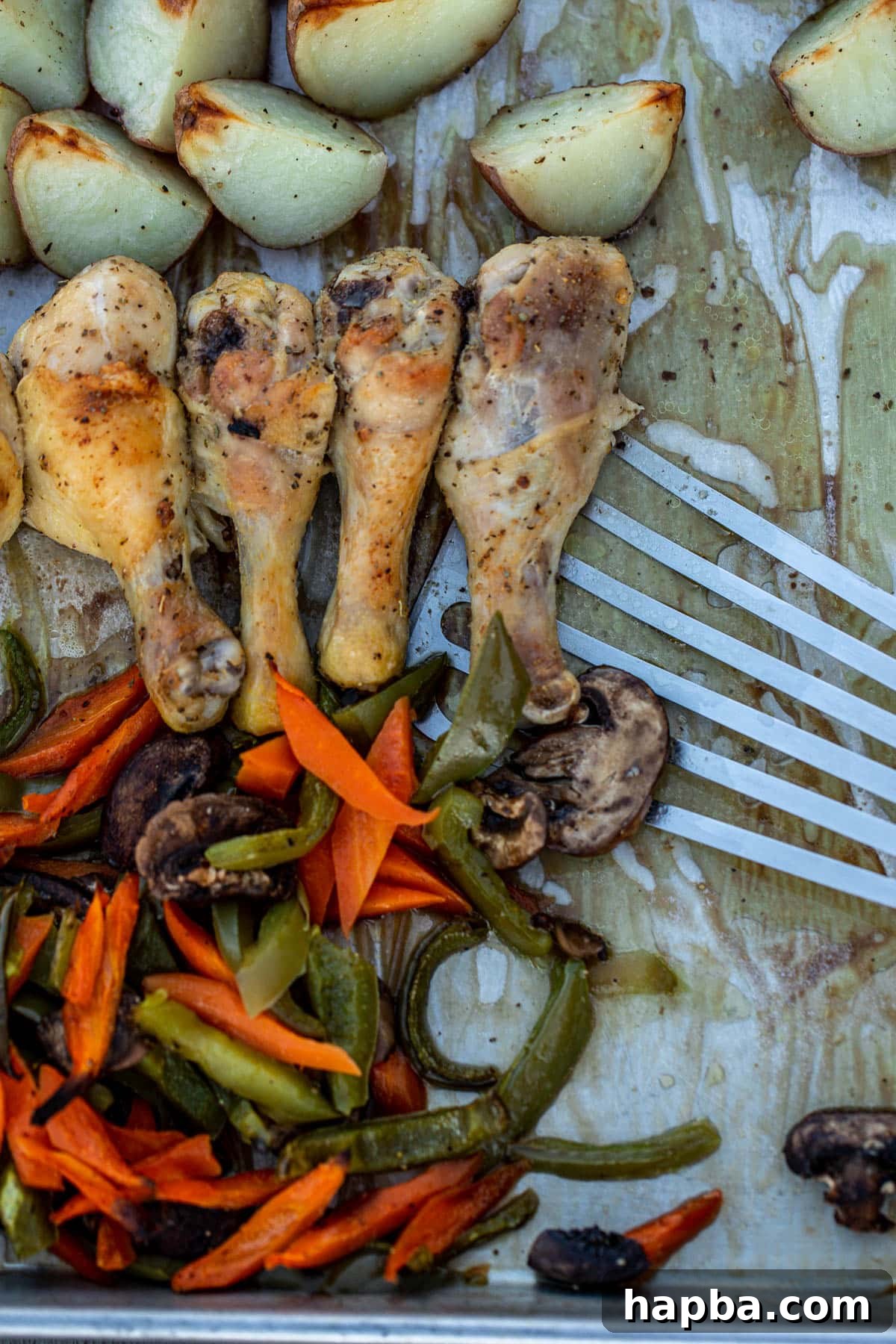 One Pan Golden Roasted Chicken and Vegetables 7 A close-up of a serving of roasted chicken, potatoes, and vegetables being dished onto a plate using a fish spatula, emphasizing the tender texture and appealing presentation of the meal.