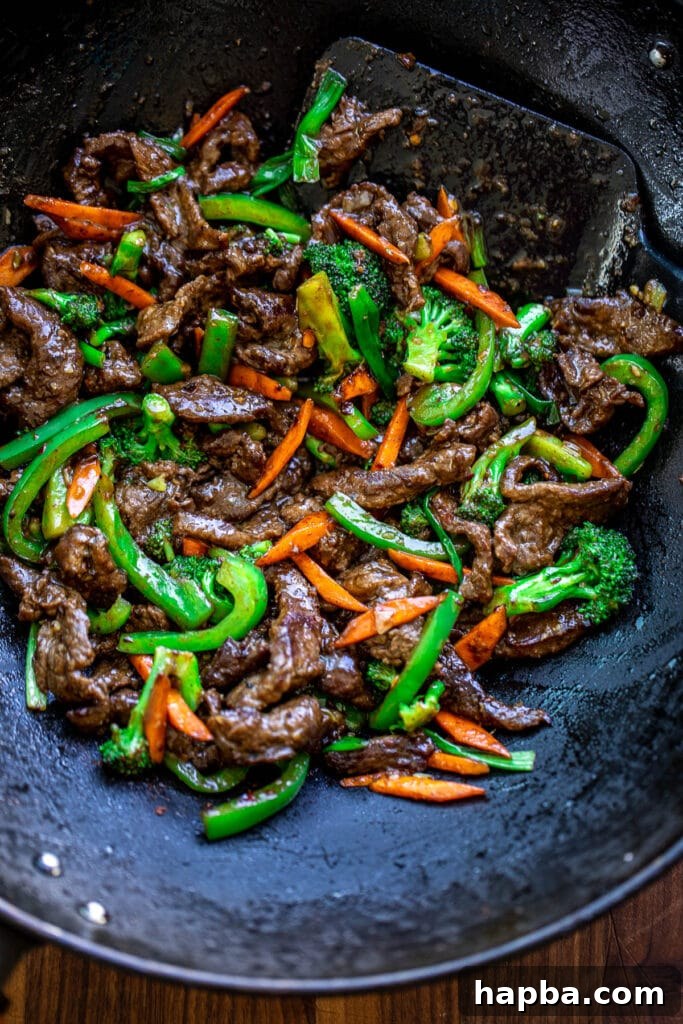 Beef and vegetable stir fry in wok, coated in savory sauce