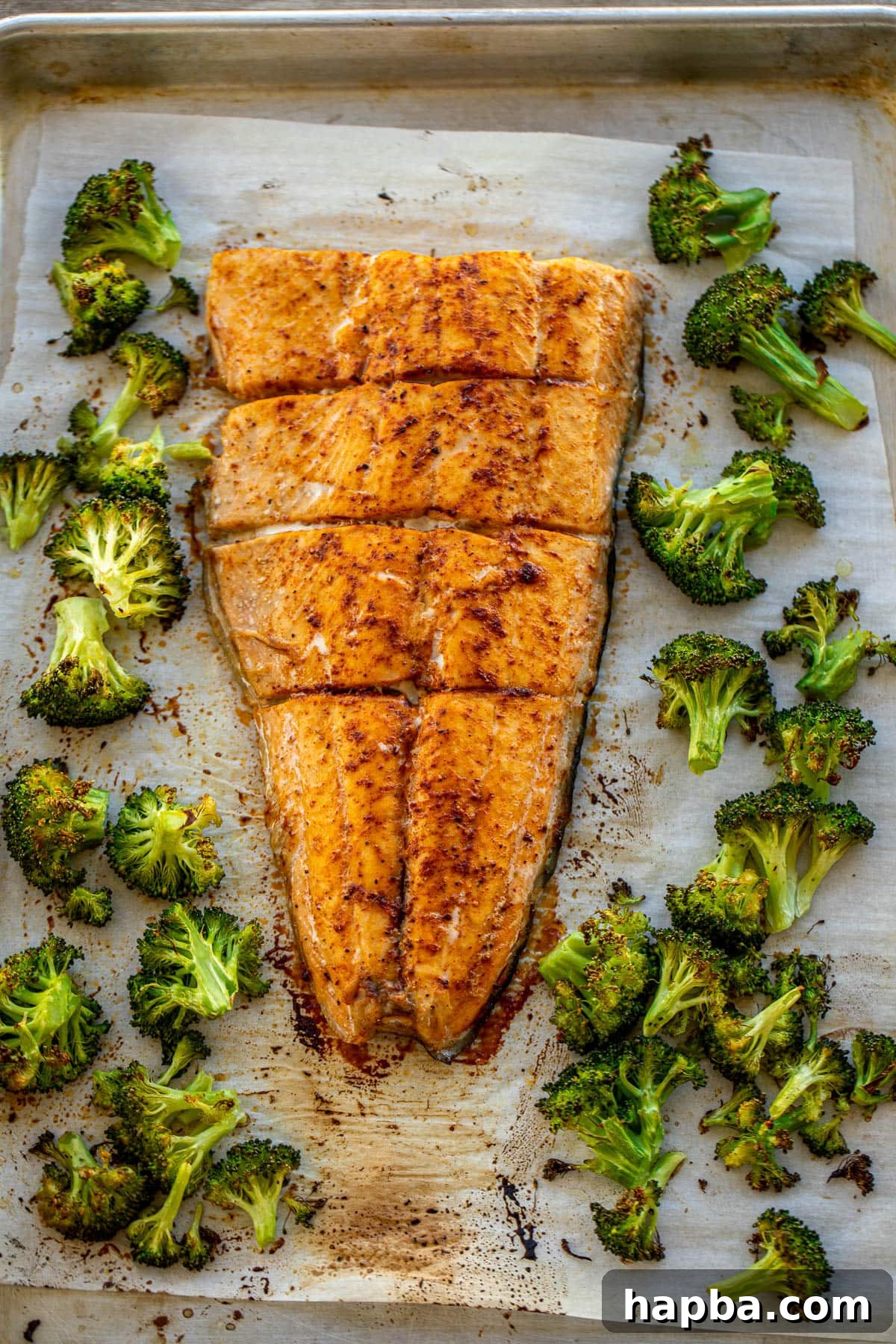 Effortless Sheet Pan Salmon and Broccoli 2 Large salmon fillet and roasted broccoli on a sheet pan, ready to bake