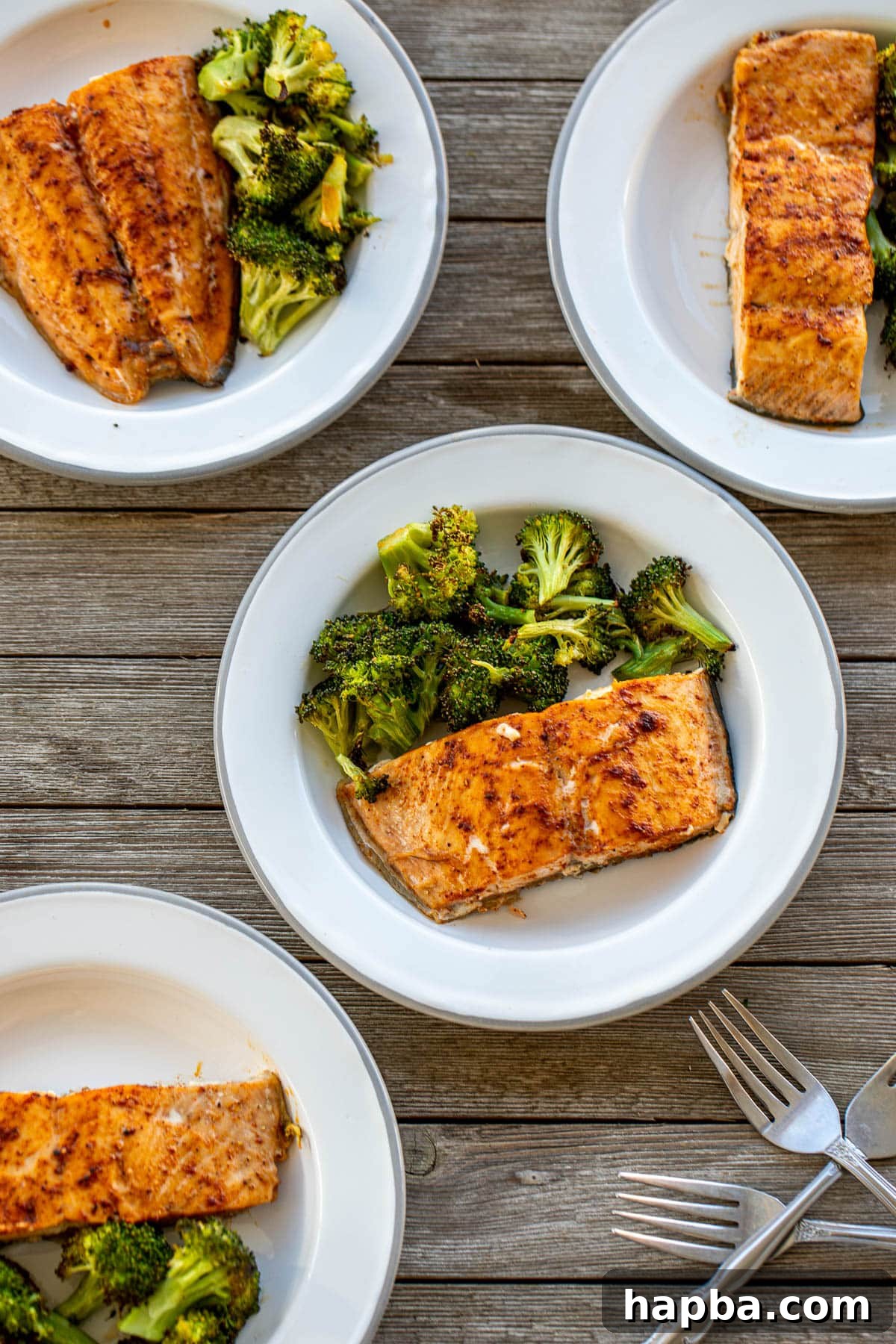 Effortless Sheet Pan Salmon and Broccoli 4 Different plates showcasing baked salmon and roasted broccoli