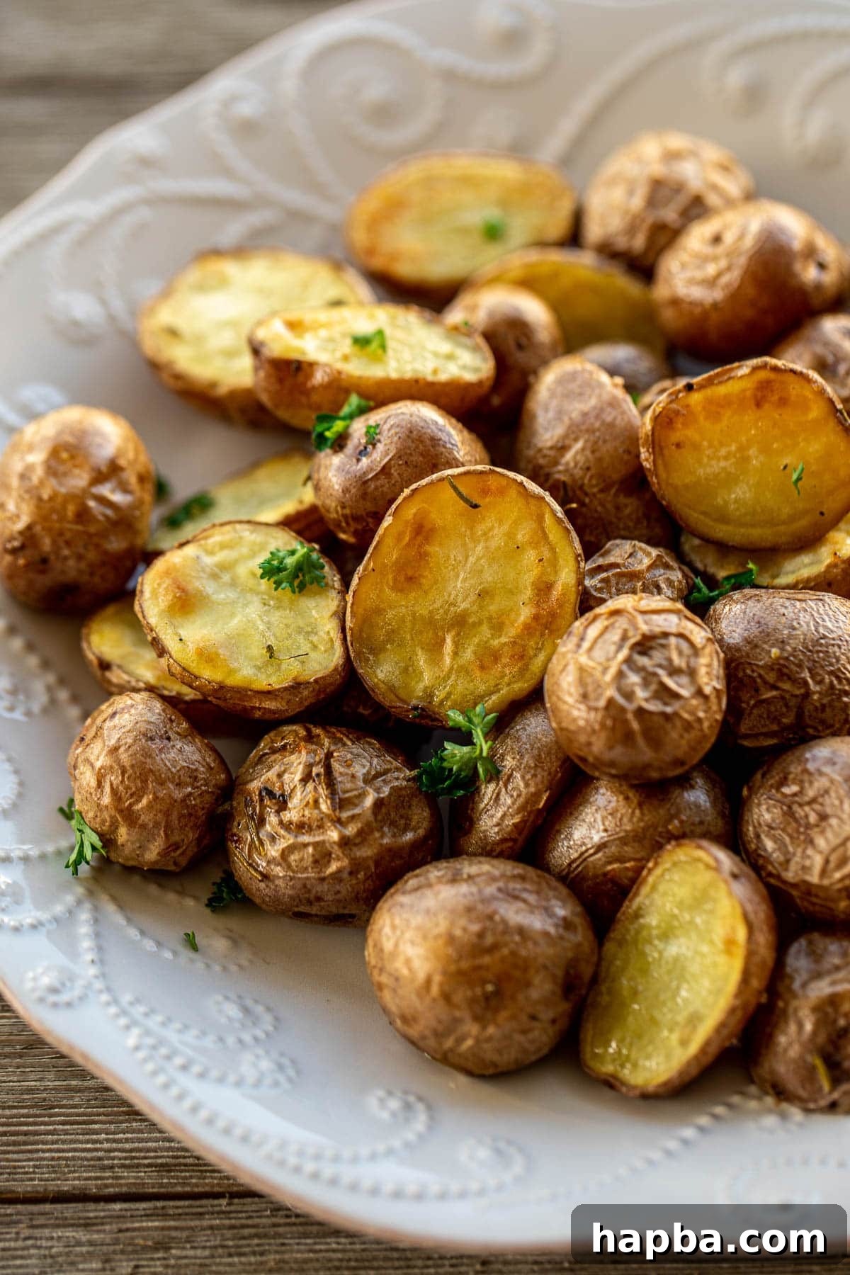 Close up shot of golden-brown roasted potatoes with garlic and rosemary, showcasing their crispy skin