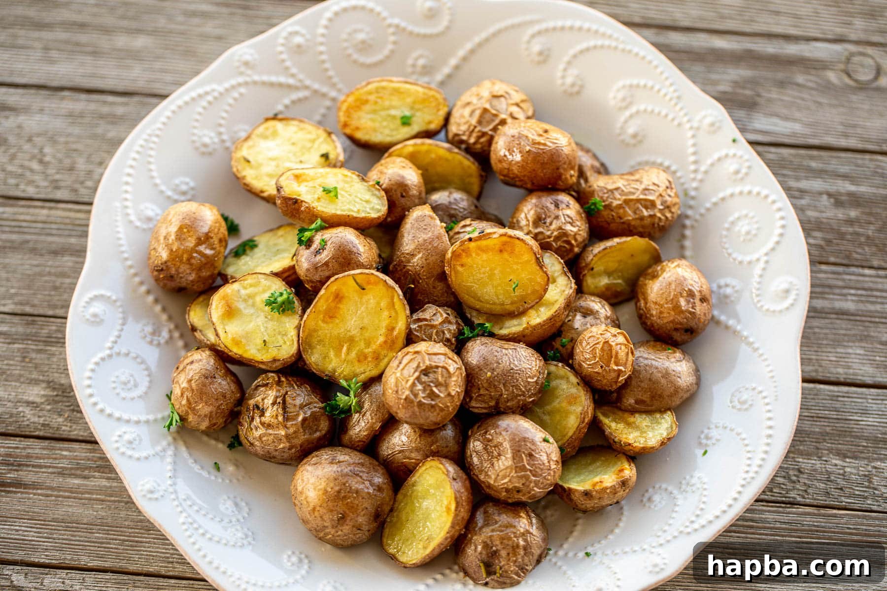 Landscape view of a baking sheet filled with perfectly roasted baby potatoes, glistening with oil and herbs