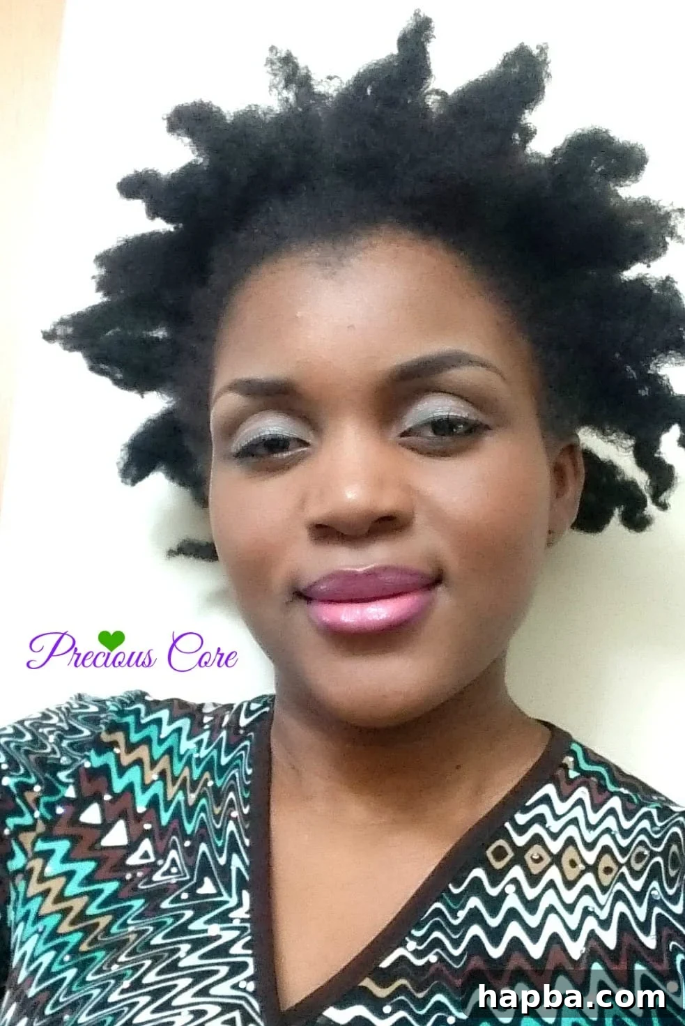 A woman with her natural hair styled in a bantu knot out, showing soft, voluminous curls.