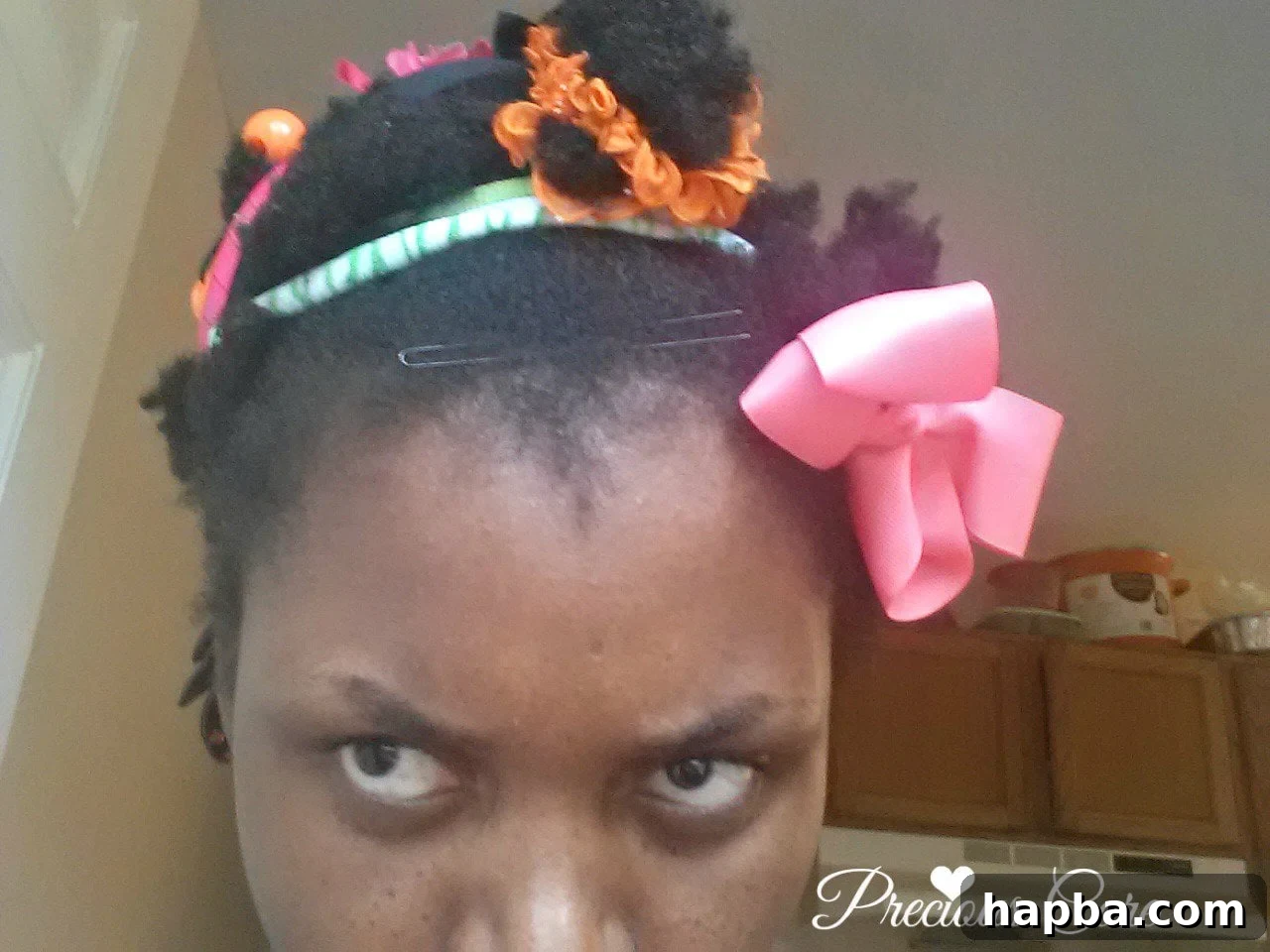 A photo of a woman's hair styled by her young daughters, adorned with colorful accessories.