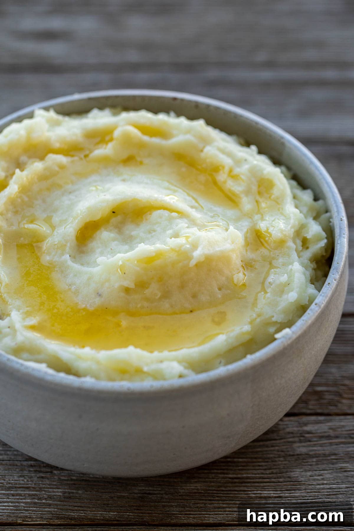 Velvety Buttermilk Mash 5 A bowl of creamy buttermilk mashed potatoes topped with melted butter and fresh herbs.